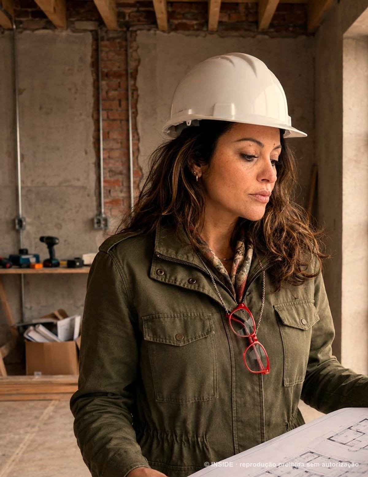 Sara Rollemberg, fundadora da INSIDE, de capacete e com a planta do projeto em visita de obra, 2026, acervo INSIDE