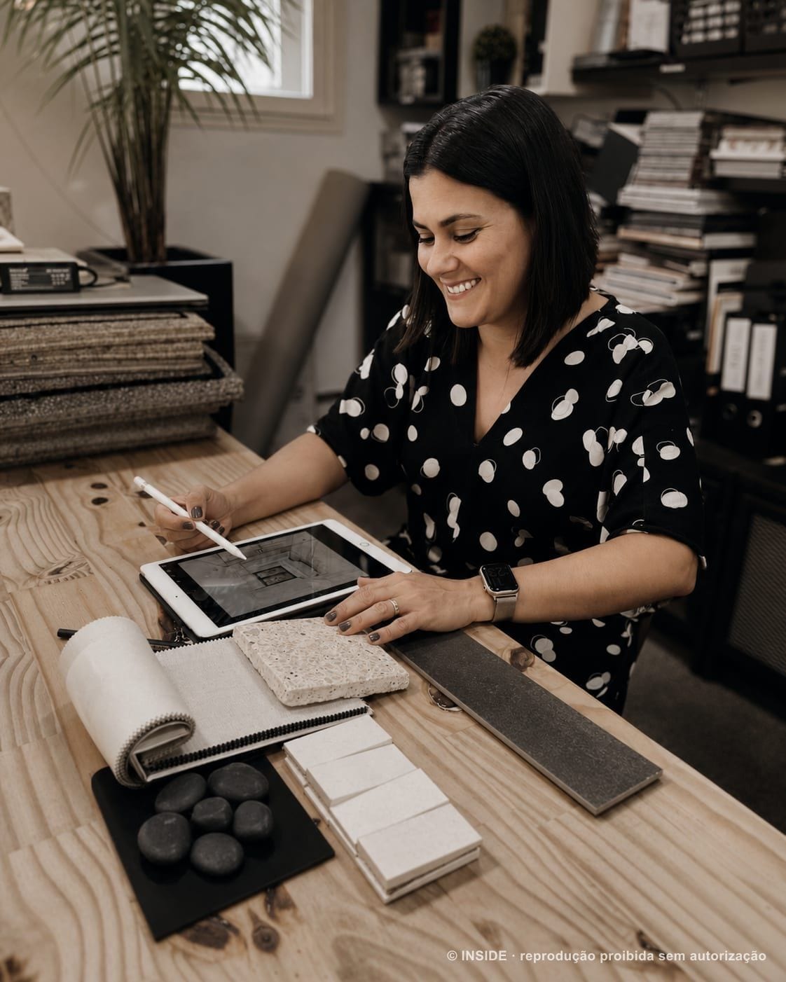 Fabiola de Souza trabalhando no iPad sobre a mesa de amostras de materiais, 2022, acervo INSIDE