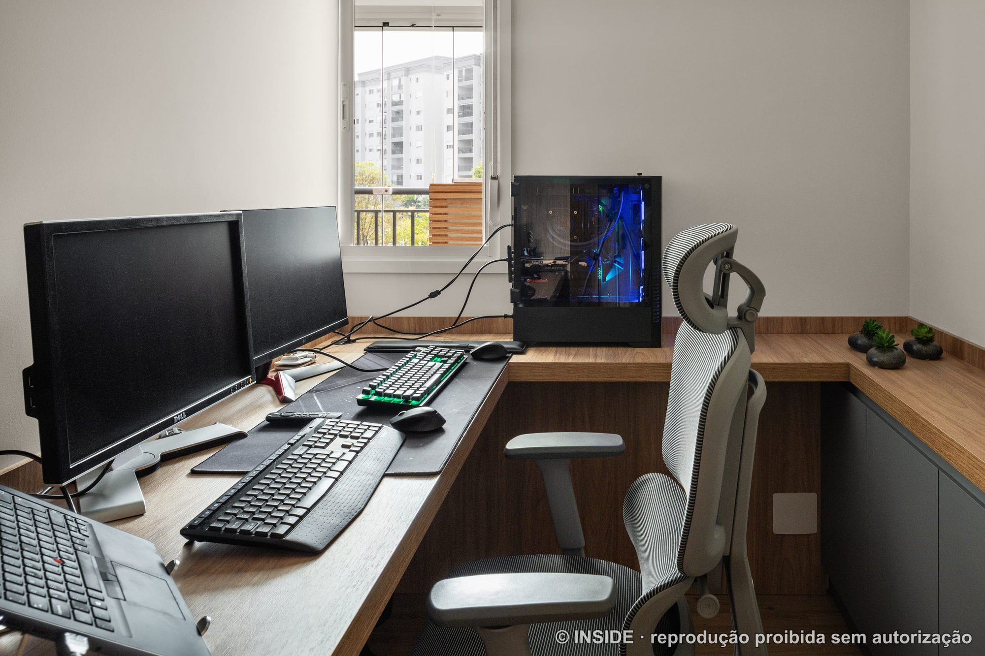 Home office com bancada em L, computador, cadeira e janela com vista da cidade, projeto INSIDE