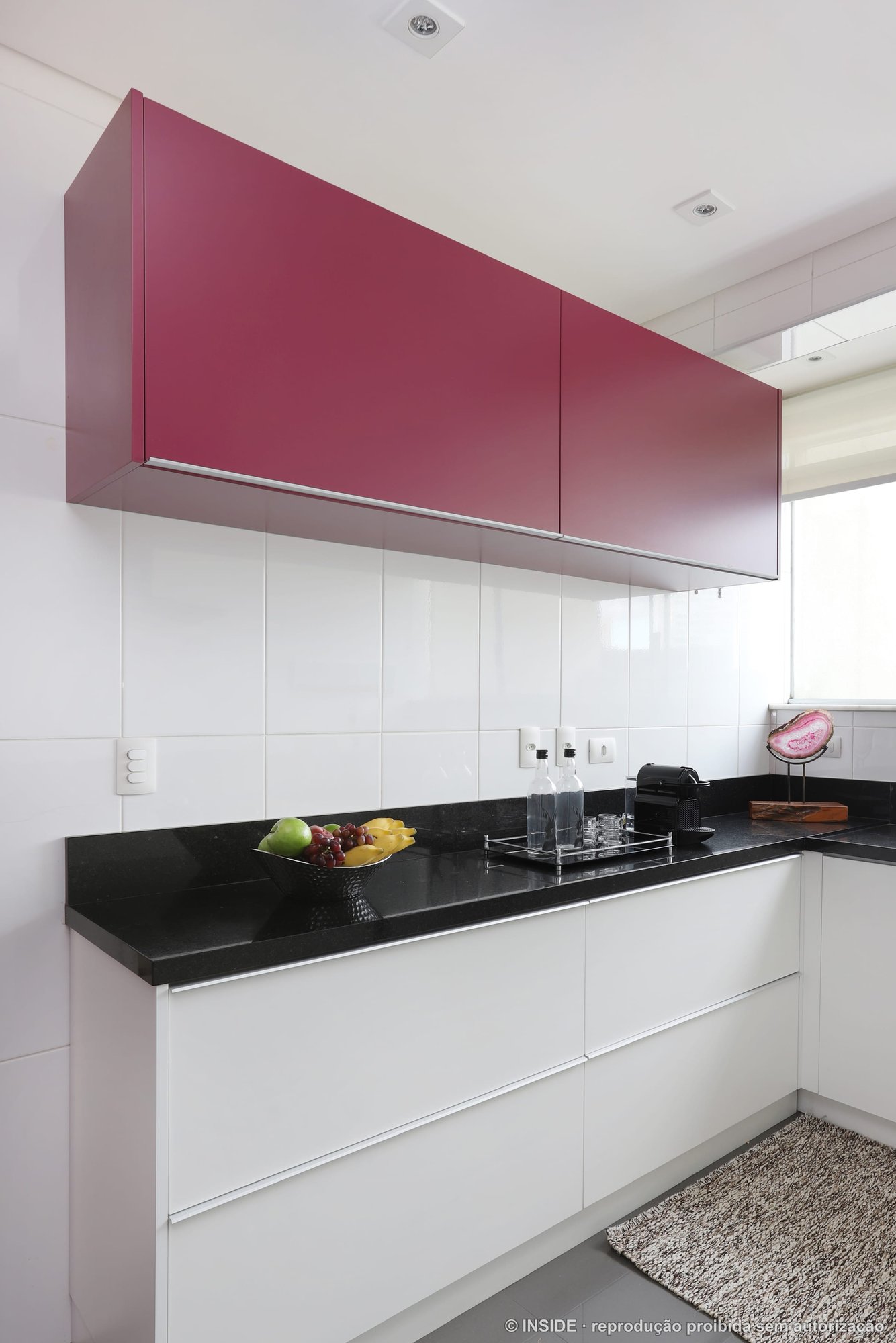 Cozinha com marcenaria branca, bancada preta e um módulo em magenta, projeto INSIDE